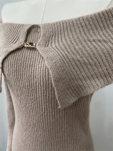 Close-up of oatmeal knit dress featuring an off-shoulder collar with golden metal buckle