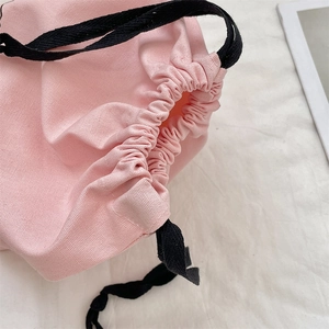 Close-up of pink linen drawstring bag showing thick fabric texture and black woven cord