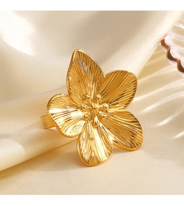Dettaglio macro dell'anello a fiore in acciaio placcato oro 18K su seta beige elegante