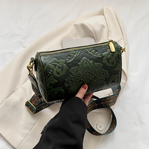 Detail of vintage green barrel bag with floral embossing and ethnic style wide strap