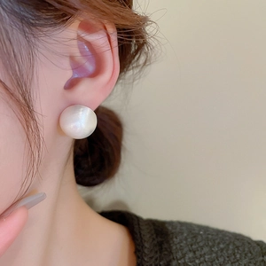Close-up of elegant white pearl stud earring worn by model with a soft pearl finish
