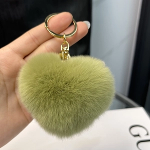 Detailed view of heart-shaped rabbit fur keychain in avocado green with golden ring