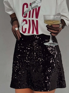 T-shirt blanc à motif graphique rouge porté avec une mini-jupe noire à paillettes pour femme