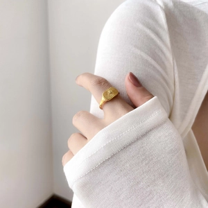 Close-up of a gold oval signet ring with sunburst pattern and crystal on a finger