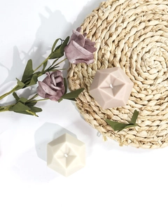 Top view of geometric polyhedron scented candles in white and beige on a woven mat