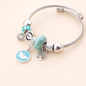 Detail of silver plated steel bracelet with light blue butterfly and tree of life charms