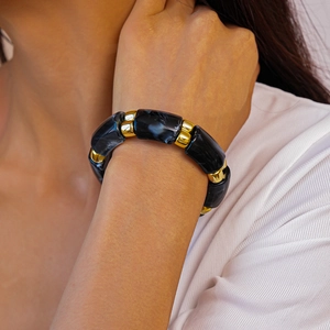 Detail of acrylic marble bead bracelet with gold metal spacers worn by a model