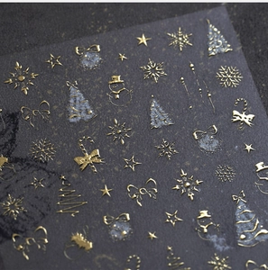 Detail shot of golden 3D embossed Christmas nail stickers with snowflakes and trees