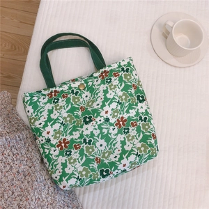 Détail du sac à lunch en coton floral avec poignées vertes et bouton-pression doré