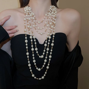 Detail of layered long pearl necklace with golden beads on elegant black dress