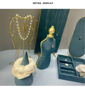 Detail display of dark green velvet jewelry stand set with gold metal accents