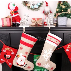 Linen Christmas stockings with Santa and snowflake motifs hanging on fireplace