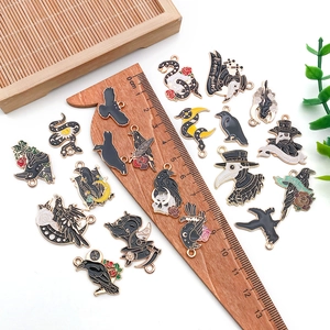 Flat lay of gothic enamel charms including plague doctor and raven motifs with a ruler