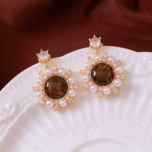 Macro detail of retro gold earrings with tiger eye resin, pearls and zircon accents