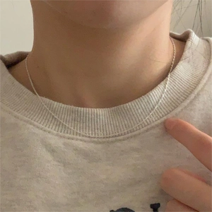 Detail of minimalist 925 sterling silver water wave chain necklace on a model's neck