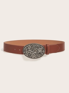 Detailed macro view of a vintage brown leather belt with an engraved silver oval buckle
