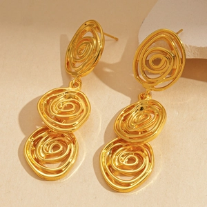 Détail de boucles d'oreilles spirales dorées sur pierre texturée, design artistique