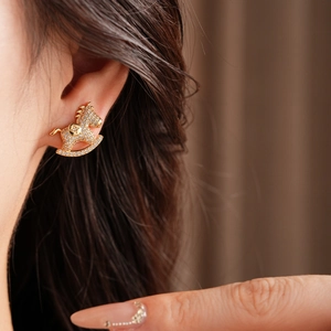 Close-up of sparkling crystal-encrusted rocking horse stud earring on model's ear