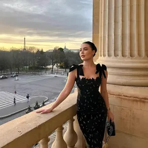 Elegant black lace bodycon dress with velvet bow straps against a Parisian balcony backdrop