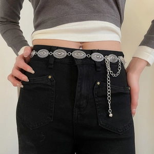 Vintage silver metal waist chain with oval engraved charms on black denim jeans