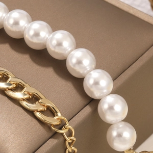 Macro detail of glossy baroque pearls and polished gold chain on a textured jewelry box