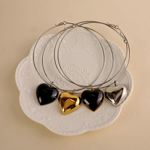 Macro shot of minimalist heart pendant necklaces in black, gold and silver on a white tray