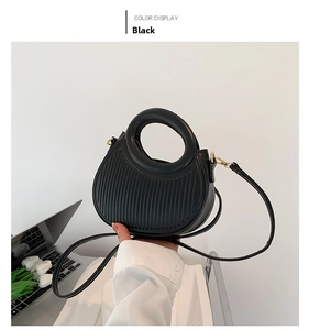Detail of black semi-circle saddle bag with vertical stripes and gold metal hardware