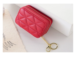 Detail of red quilted leather mini cosmetic bag with golden zipper and keychain hook