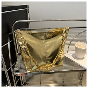 Detailed view of a metallic gold bucket bag with a stylish chain strap on a metal stand