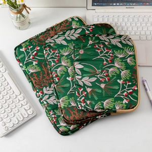 Three-piece embroidered floral laptop sleeve set in dark green satin on a white desk