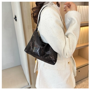 Détail d'un sac hobo à paillettes noires porté par un mannequin dans un cadre minimaliste