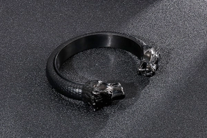 Detail of a black punk wolf head bangle featuring scale texture and engraved animal motifs