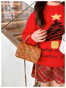 Close-up of brown quilted crossbody bag with chain strap worn with Christmas sweater