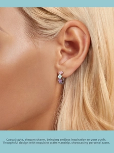 Close-up of small sterling silver hoop earrings with colorful enamel flowers on model