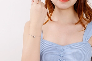 Close-up of a silver titanium steel letter pendant bracelet on a woman wrist