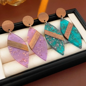 Vue macro de boucles d'oreilles en bois et résine en forme de feuille avec feuille d'or