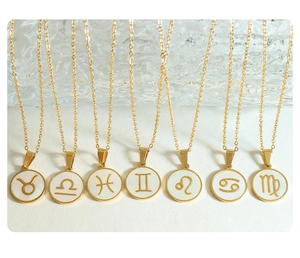 Detail of seven gold zodiac pendant necklaces featuring white shell inlay on white background