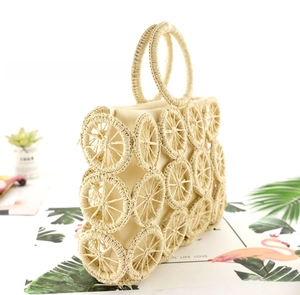 Detail of hand-woven straw bag featuring hollow circular patterns and ring handles