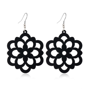 Macro detail of black hollow flower wooden drop earrings with silver metal hooks