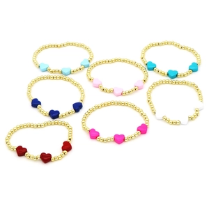 Colorful enamel heart bead bracelets set with gold round beads on white background