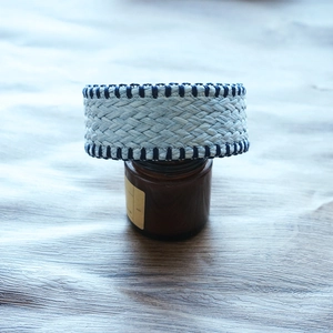 Detail of woven raffia headband in light blue with dark blue edges on wood surface