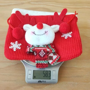 Détail d'un sac cadeau de Noël en tricot rouge avec renne, pesé sur une balance digitale
