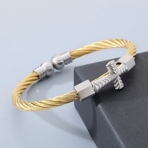Detail of twisted cable bangle in gold and silver steel with a cross charm design