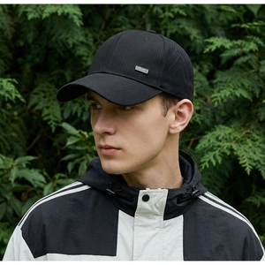 Detail of a black sports cap with a metal logo plate showing outdoor performance fabric
