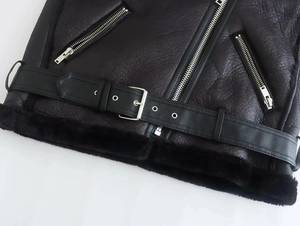 Detail of black faux leather biker jacket featuring metal zipper and adjustable belt buckle