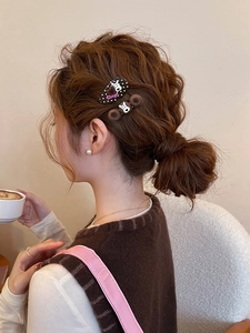 Detail of plush dog hair clips styled on a low bun hairstyle in a cozy cafe setting