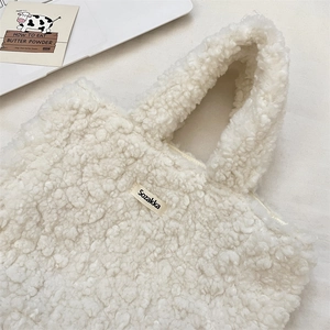 Close-up of soft plush cream tote bag with Sozakka label on a white cozy desktop