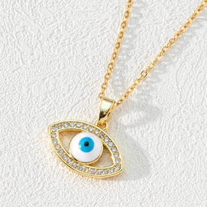 Gold plated evil eye necklace with blue zircon pendant on white ripple background