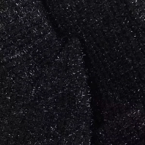 Close-up of black tweed fabric texture with shimmering silver metallic thread details