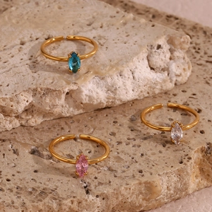 Three gold open rings with blue, pink, and clear marquise zircons on a textured stone base